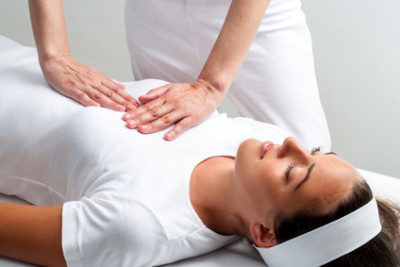 Therapist pressing with hands on womans chest at reiki session.