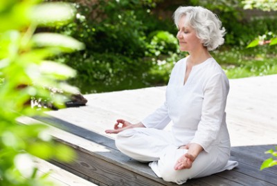 Seniorin macht Yoga im sommerlichen Garten